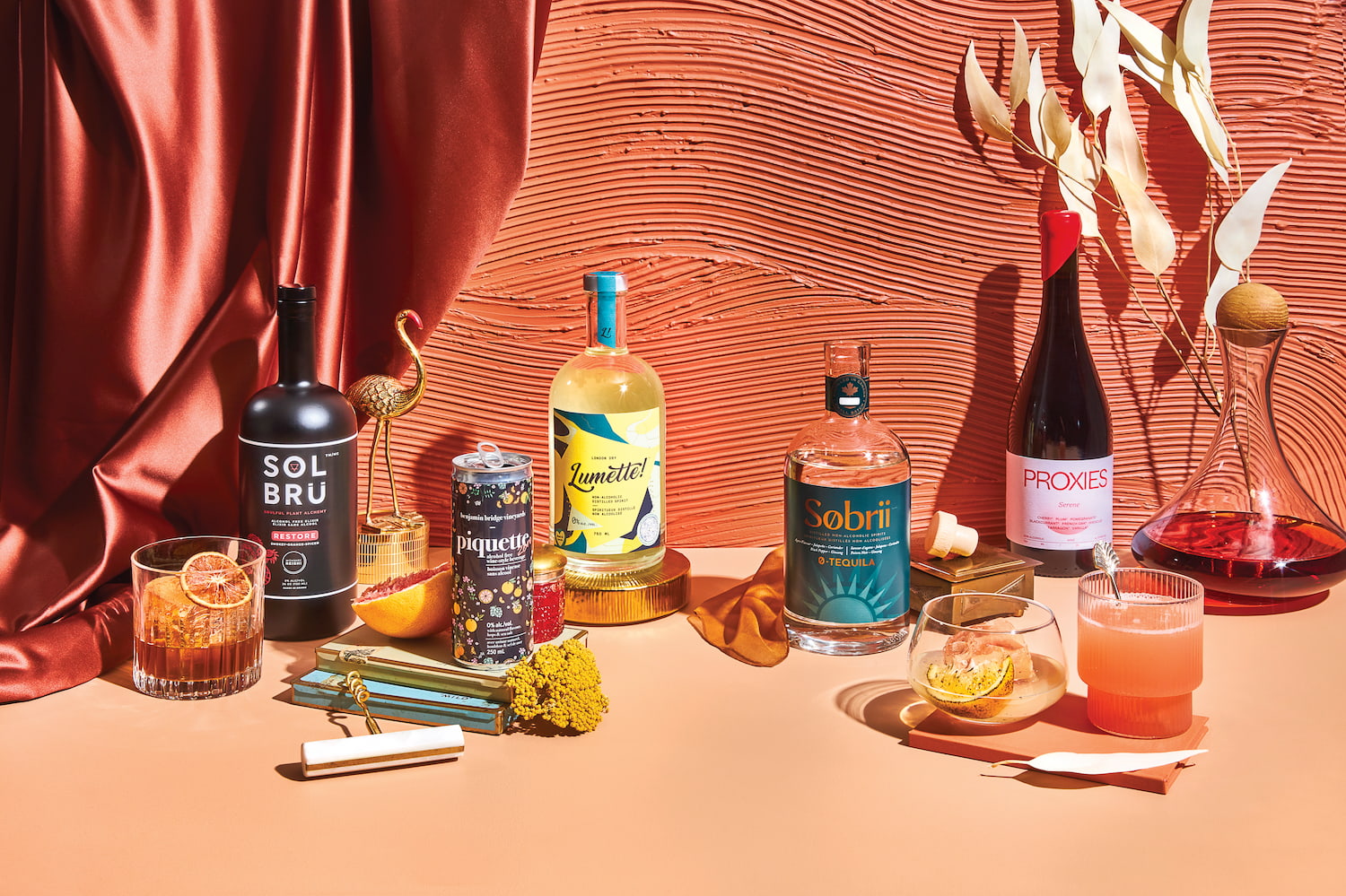 A collection of non-alcoholic spirits set against a salmon-pink backdrop
