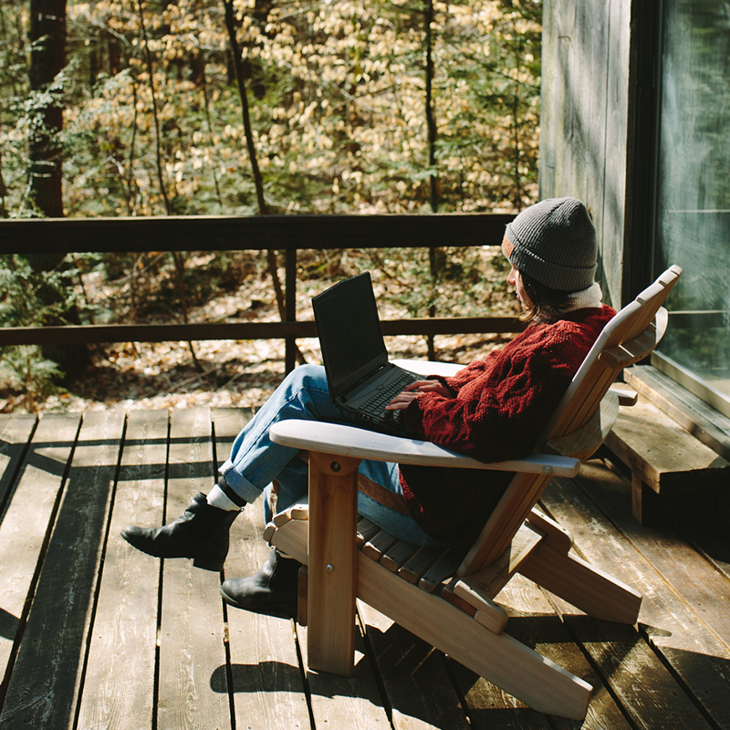 A woman sitting in a chair on a deck in the woods