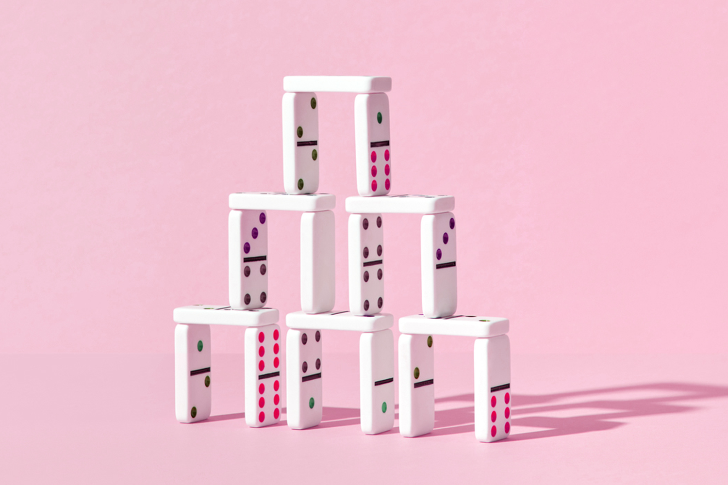 a photo of stacked dominos on a pink background