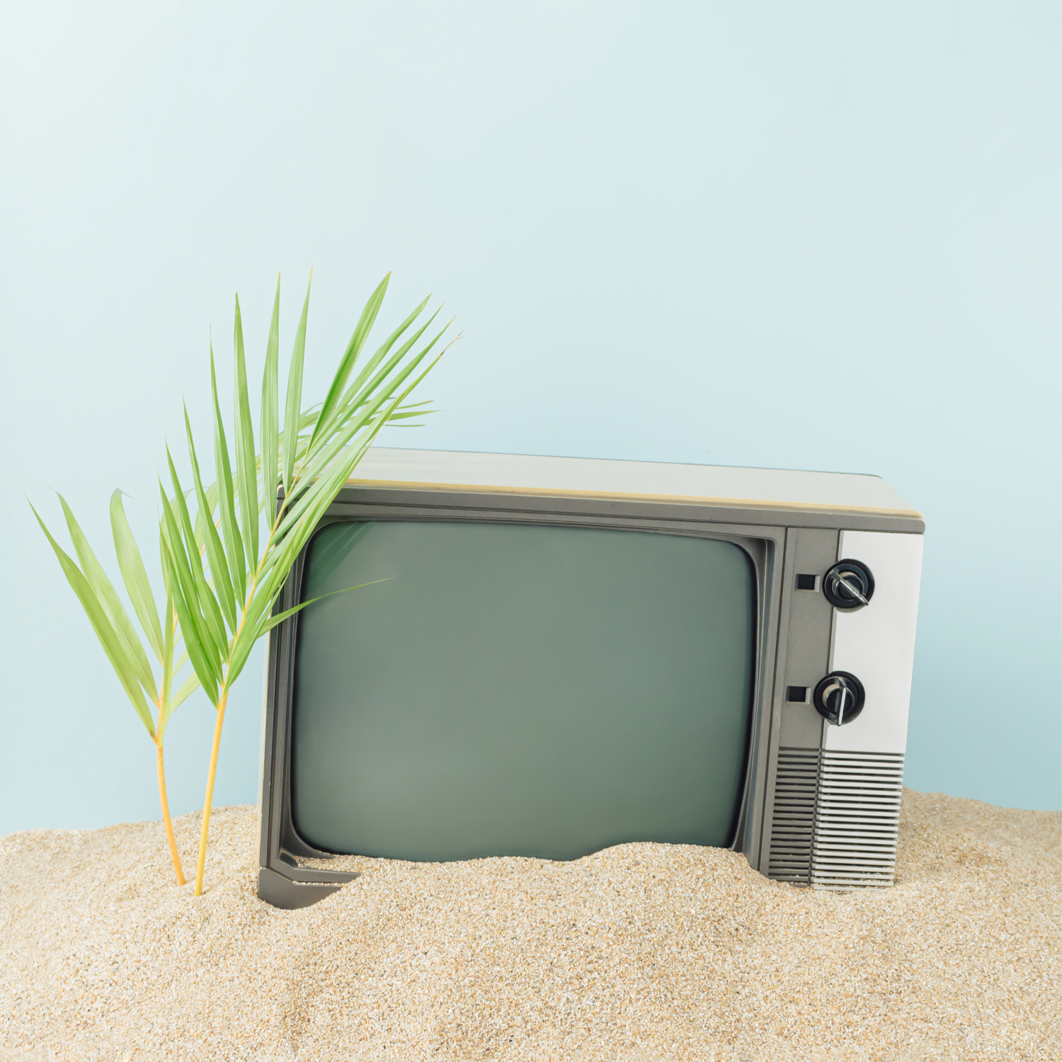 A photo of an old TV sinking in the sand