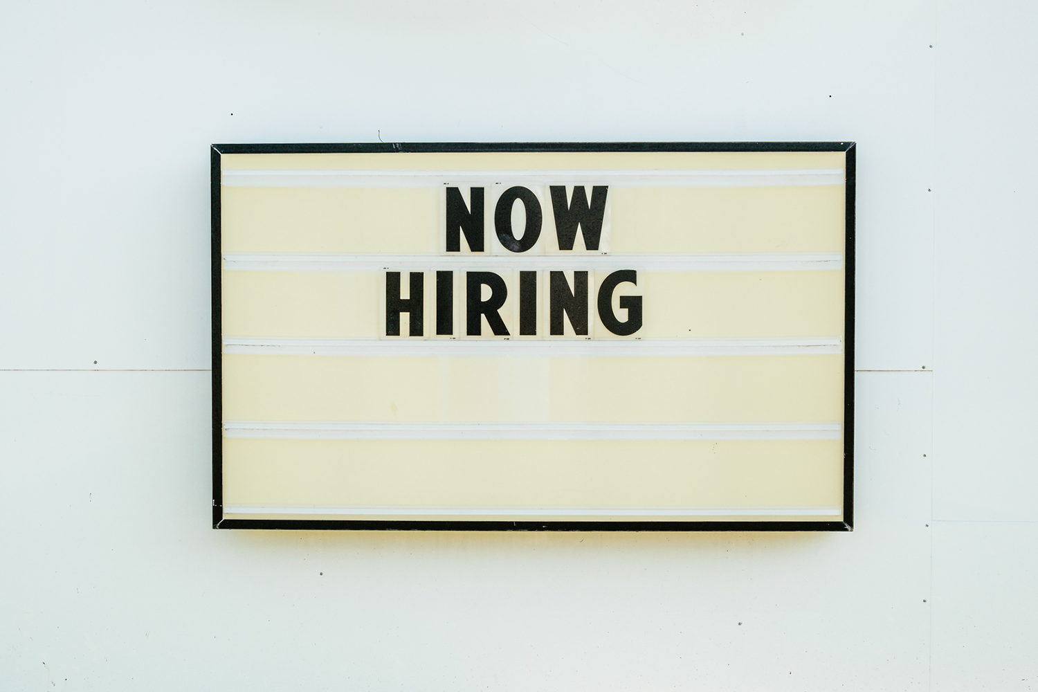 A photo of a 'now hiring' sign