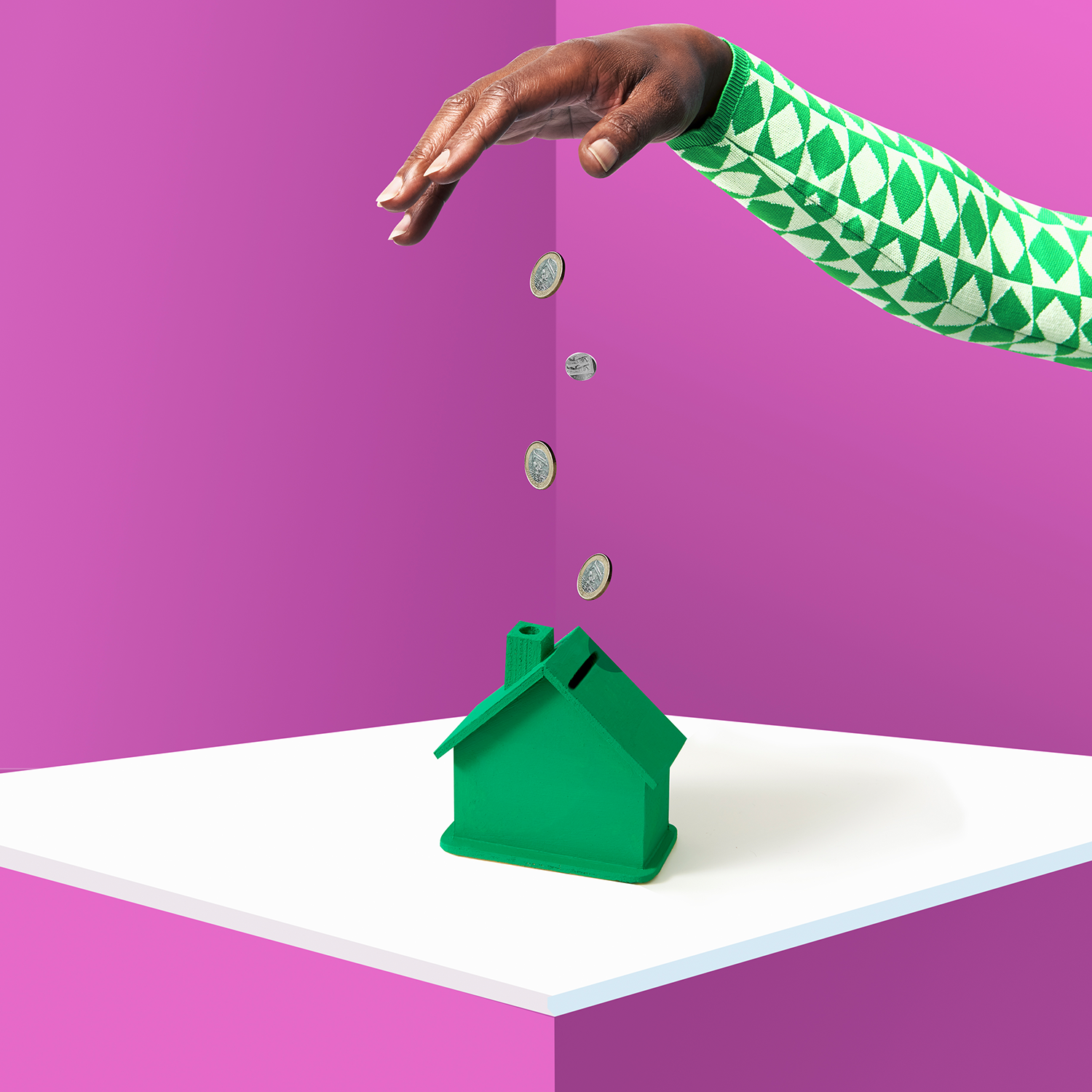 A photo of a woman putting money into a piggy bank shaped like a home