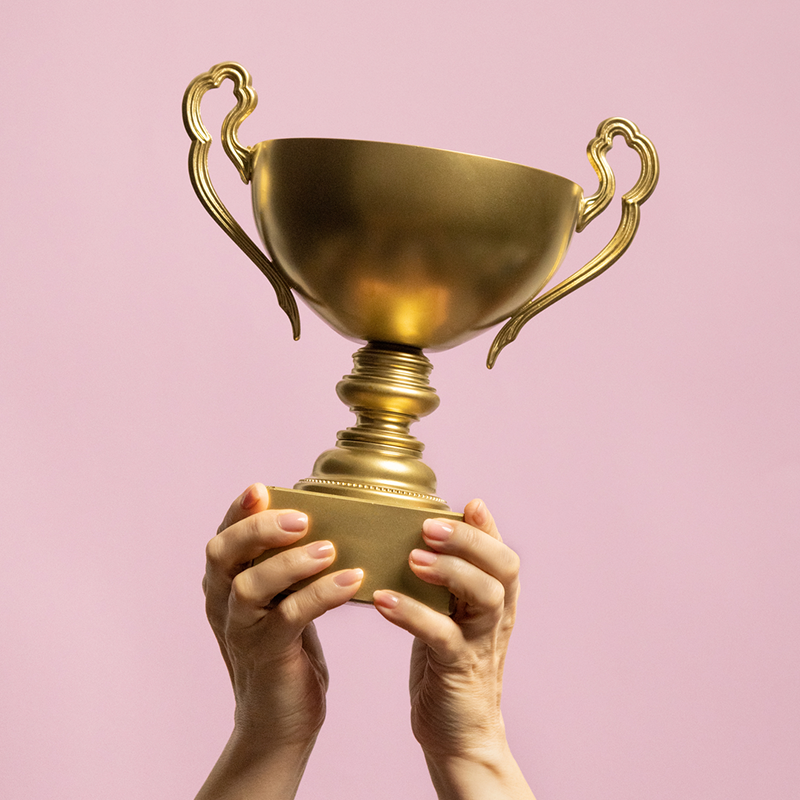 Hands holding up a gold trophy as part of an employee recognition program