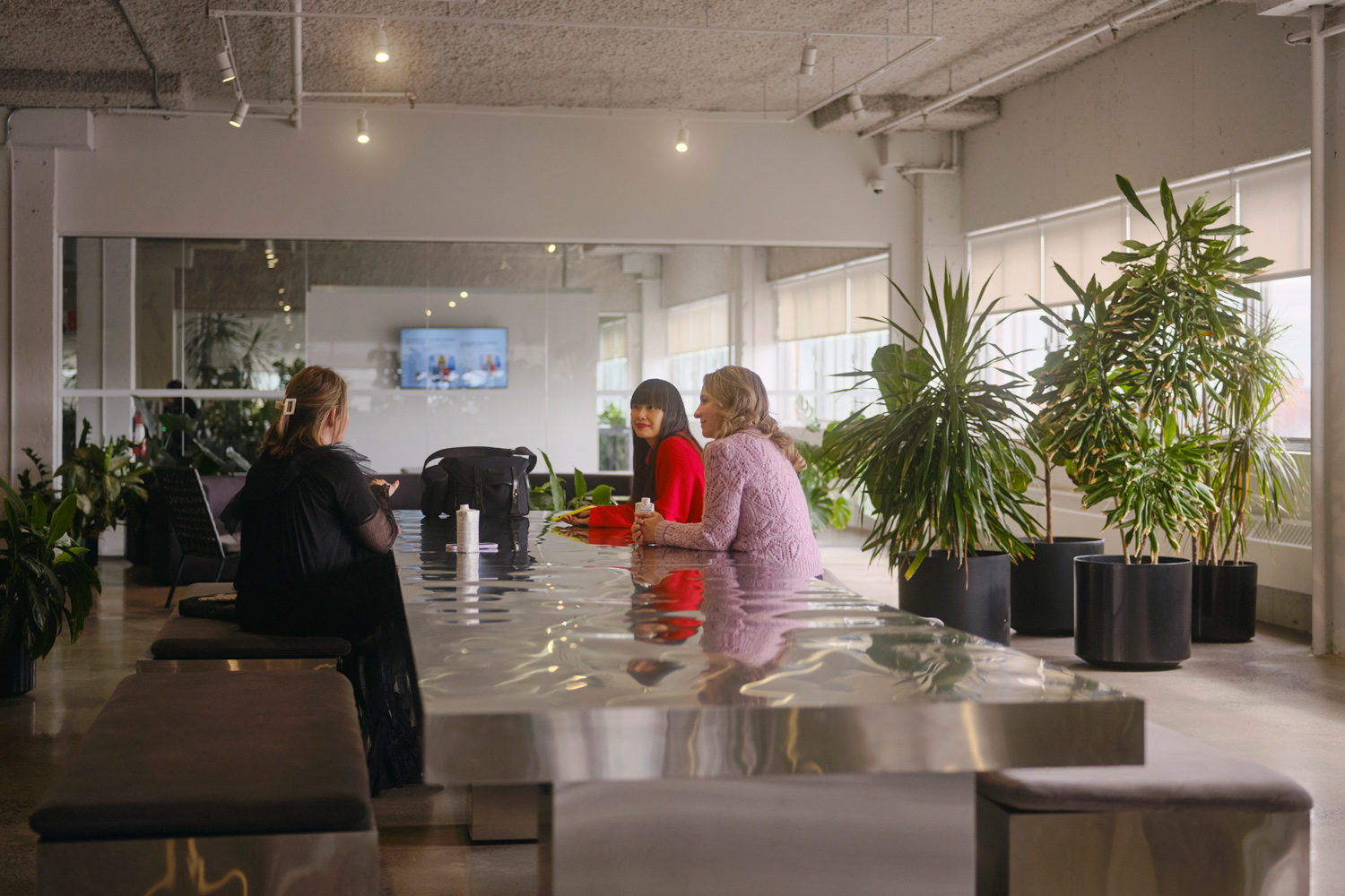 A meeting room at SSENSE's Montreal office. Three workers are sitting around a board table