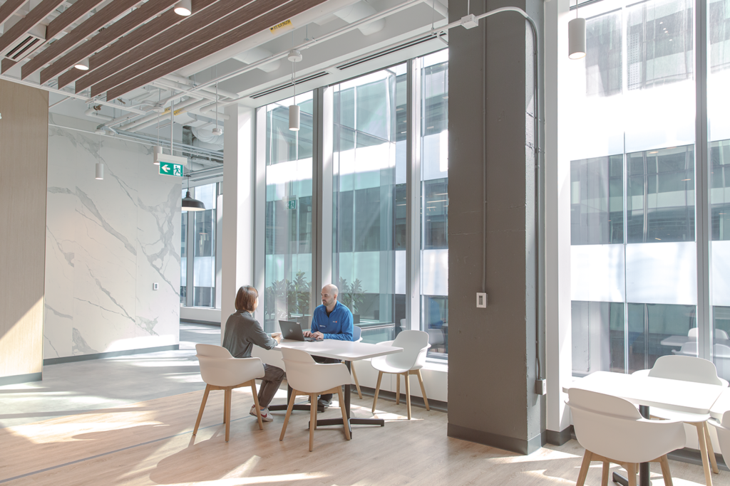 Inside BMO's new Toronto headquarters are two workers sitting at a white table near the window and talking 