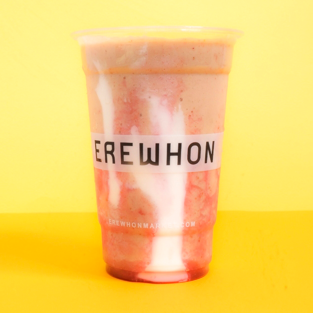 A pink smoothie in a plastic glass on a yellow background 