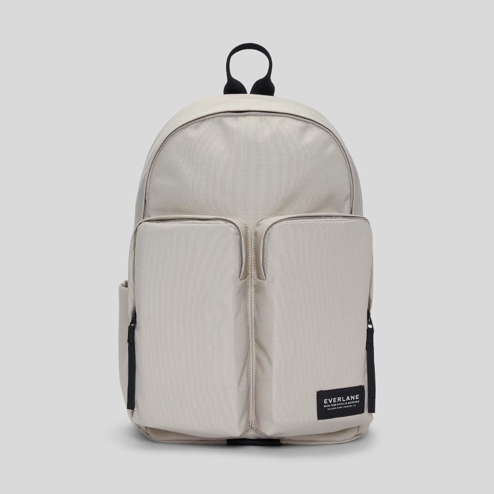 An off-white backpack with a black handle 