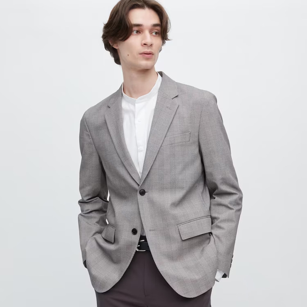 A man wearing a grey blazer on top of a white shirt looking off to one side 