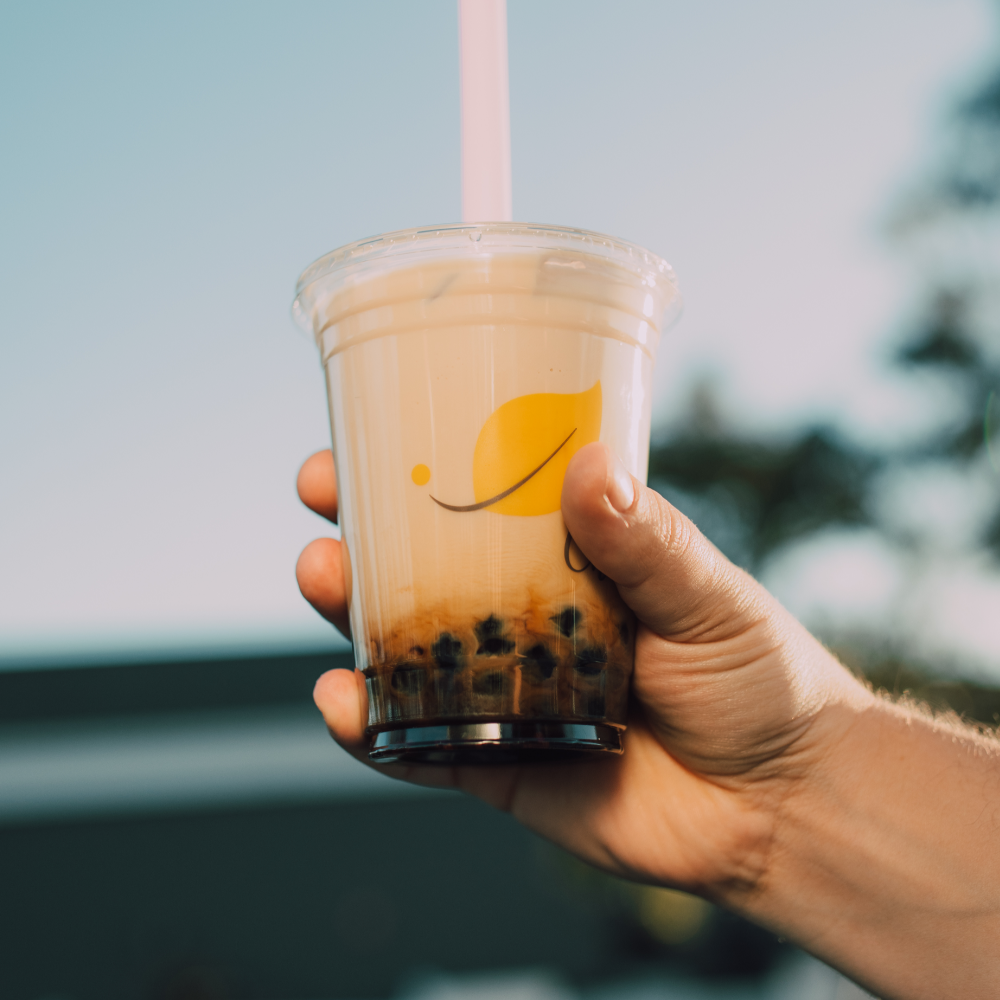 A hand holding out bubble tea