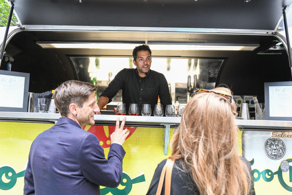 A bartender standing inside a food truck talking to two customers 