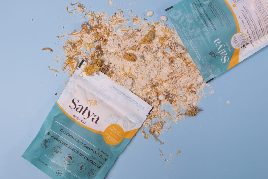 Satya Organics bath soak spilling out of a blue and white package on a bleu background 