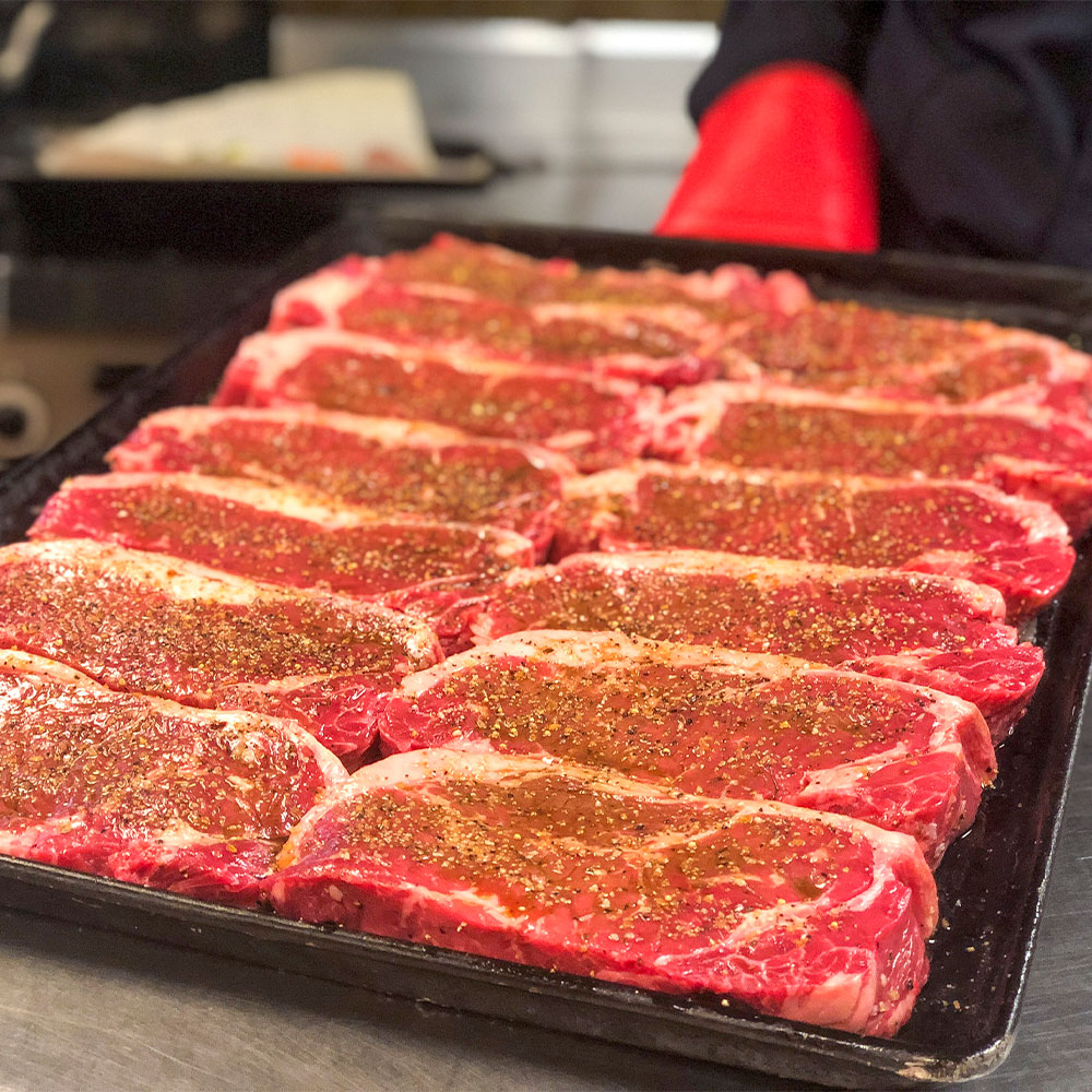 A tray of Alberta beef steaks covered in seasoning