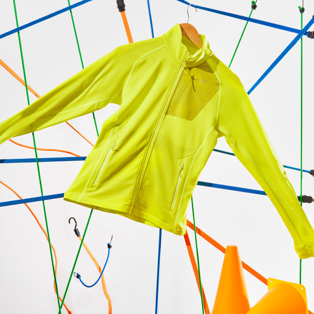 A lime green jacket on a background made of neon coloured straps, para cords and bungee cords