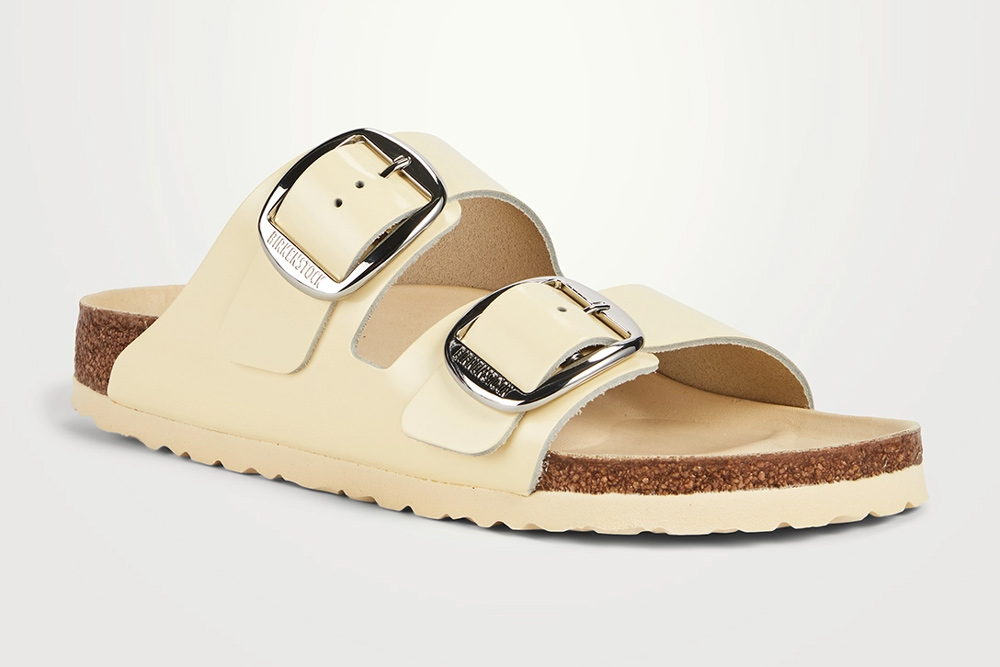 A light tan birkenstock with silver buckets and a tan sole